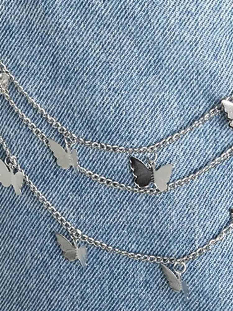 Silver butterfly charms close-up on denim