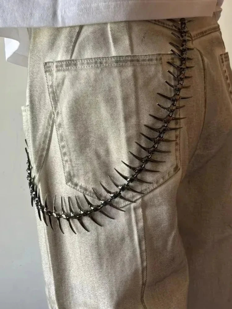 Spike pants chain worn over back pocket of beige jeans